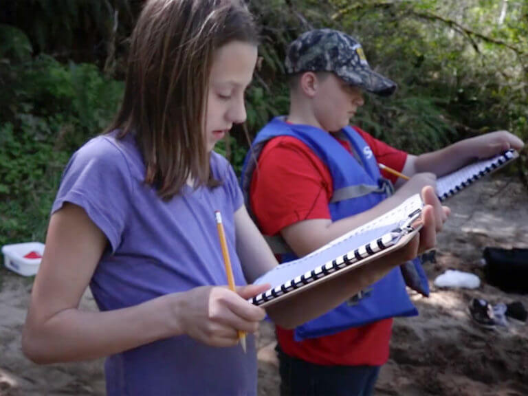 students taking notes on river bank